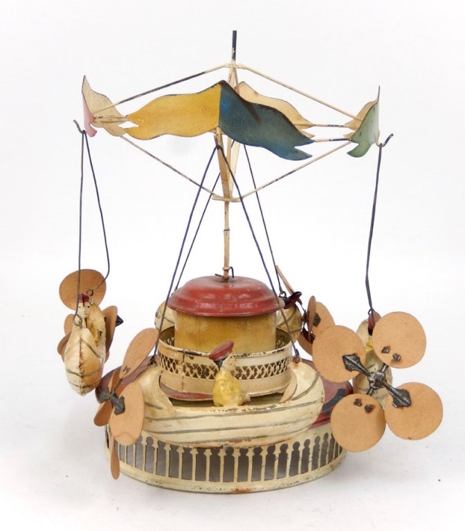 Tin windup boat carousel: Tin windup boat carousel, painted red and white, flags on top are red and green and blue and yellow, each boat has one rider and four cardboard propeller blades on back, windup mechanism works, 10 3/4