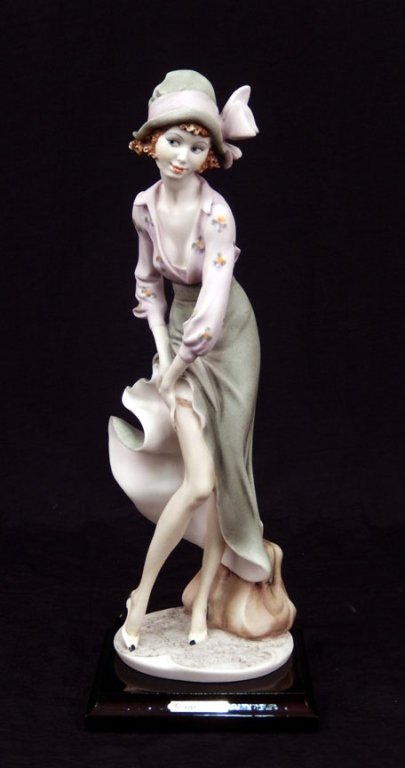 Giuseppe Armani figurine of a young lady: Giuseppe Armani figurine of a young lady, with suitcase, pulling on tights, mounted on base, signed, impressed 1991 Florence, 13 3/4" x 5"