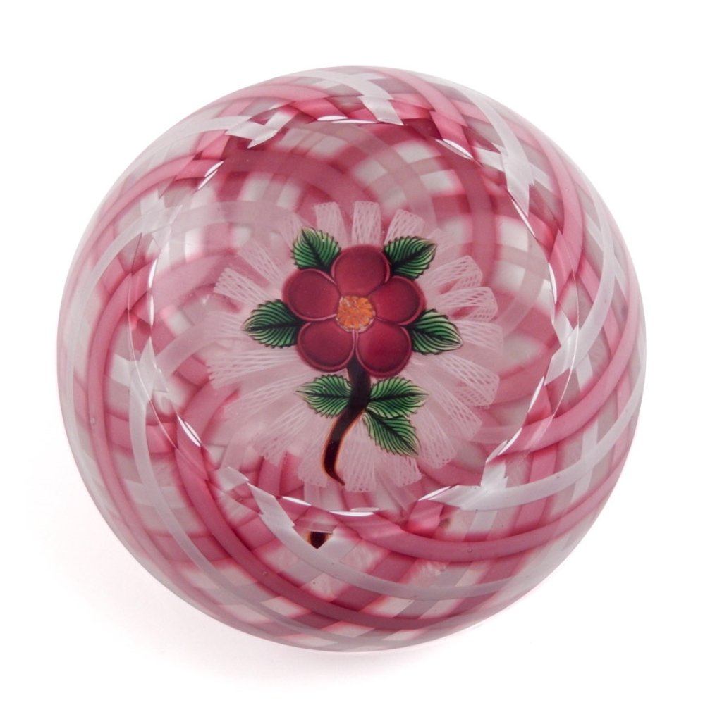 John Deacons art glass paperweight: John Deacons art glass paperweight, pink, white and red plaid effect, with a red flower with orange center and green leaves, brown stem on a split white lace disc, signature cane and dated 2004, measu