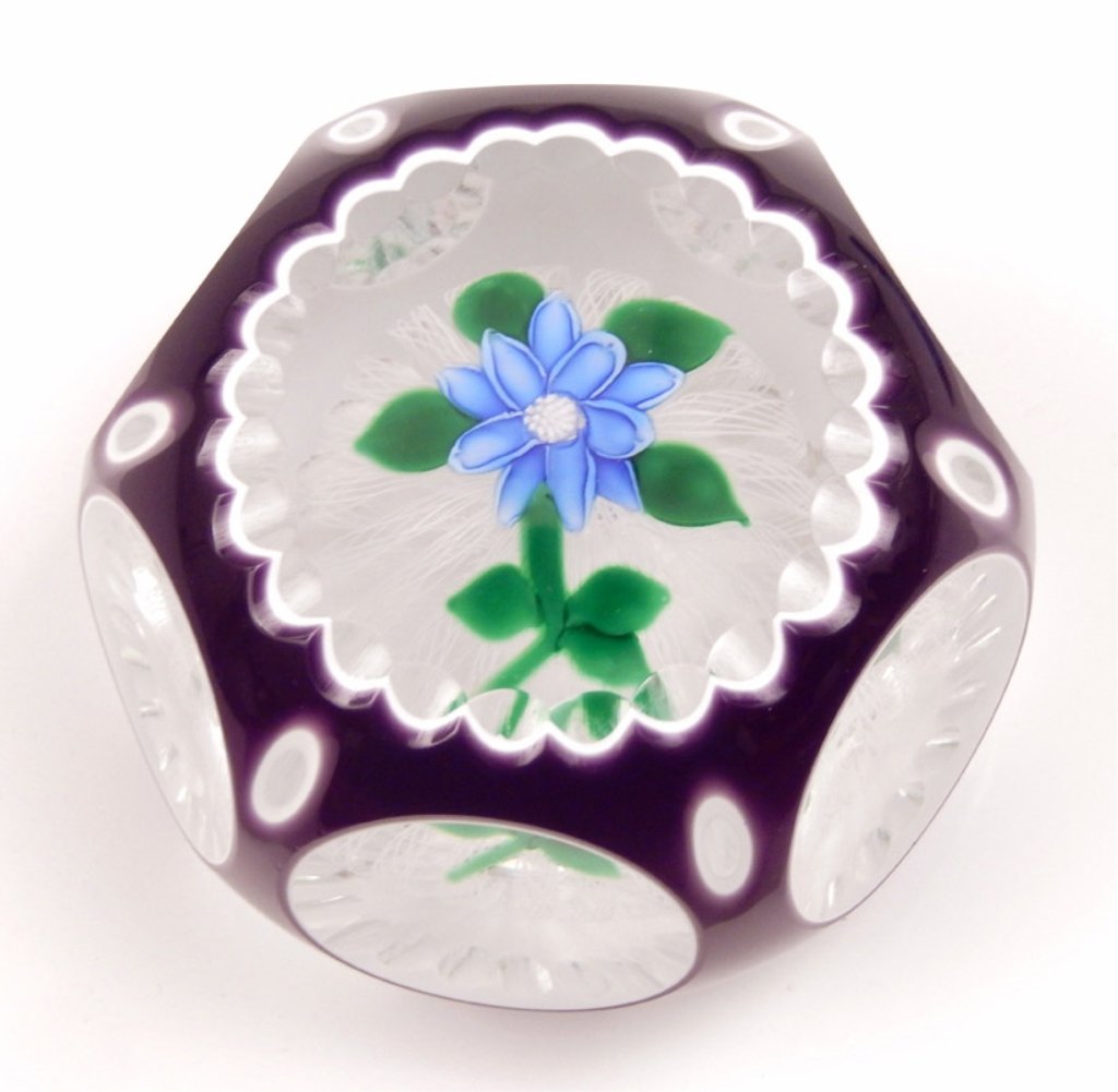 John Deacons art glass paperweight: John Deacons art glass paperweight, fancy cut purple and white double overlay, blue open flower with white center, green leaves and stem atop white latticinio cables, signature cane and dated 2000, me