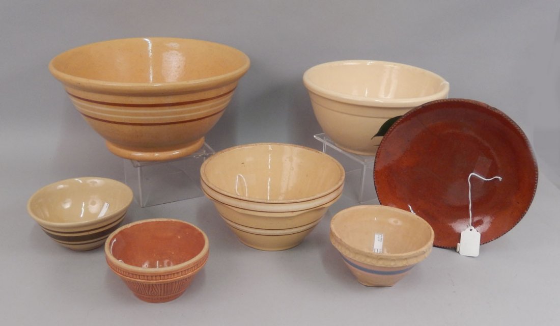Grouping of yellowware and redware pottery pieces: Grouping of yellowware and redware pottery pieces, seven pieces total, includes two yellow bowls with brown and white bands, 12 1/2" and 8 1/2", USA bowl with apple and leaves painted on front, 9 1/2"