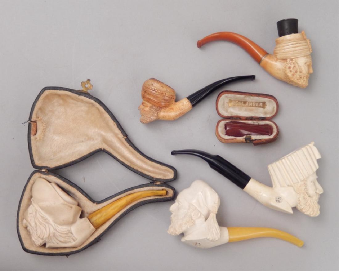 Five carved Meerschaum pipes and amber cigar holder: Five carved Meerschaum pipes and an amber cigar holder, includes one of a pirate head in fitted case, four other carved male heads, and an amber cigar holder in fitted case, meerschaum pipe case measu