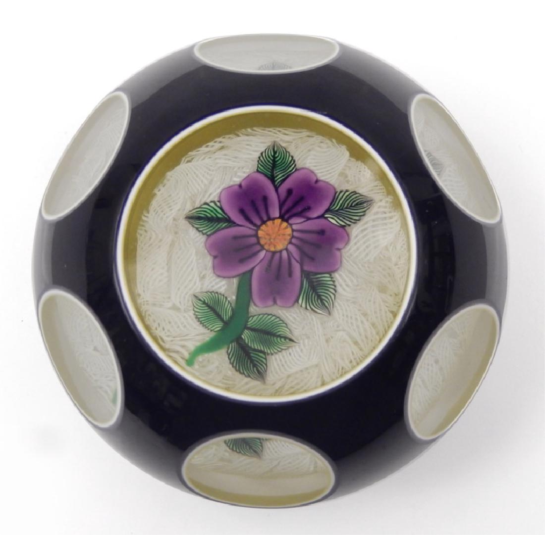 John Deacons art glass paperweight: John Deacons art glass paperweight, triple overlay black/white/lime green, with a purple and orange flower, green leaves and stem on an upset white muslin ground, JD signature cane dated 2004, measure