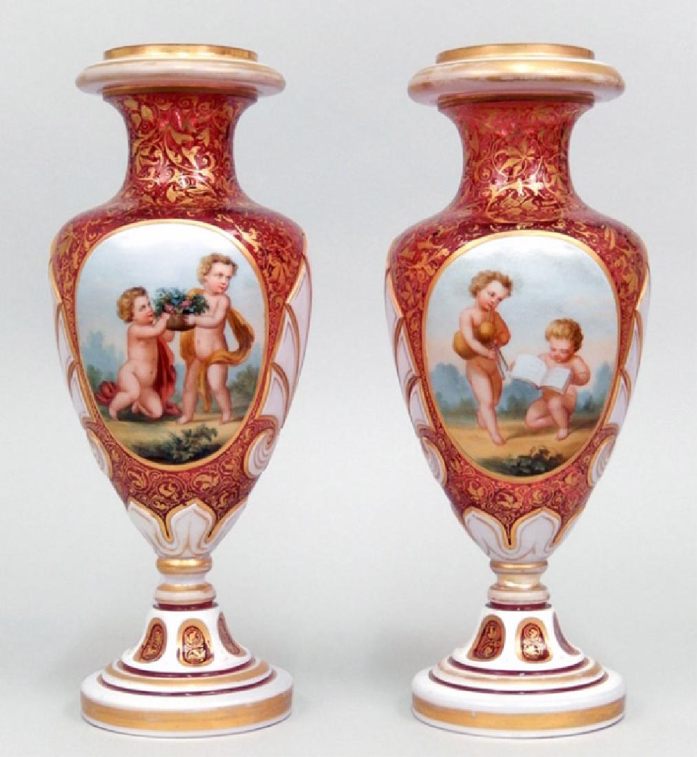 Pair of antique cranberry Bohemian glass vases: Pair of antique cranberry Bohemian glass vases, white cut to cranberry, heavy gilt foliate decoration, center cherub scenes, 10 1/4" high