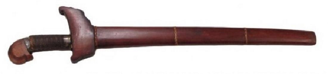 A MORO KRIS SWORD: With rare pommel form, likely Tausug. The exotic hardwood grip with the arched banati pommel with chamfered edges and hooked, stepped terminal, with engraved silver band. With intricate cord-wrapped g