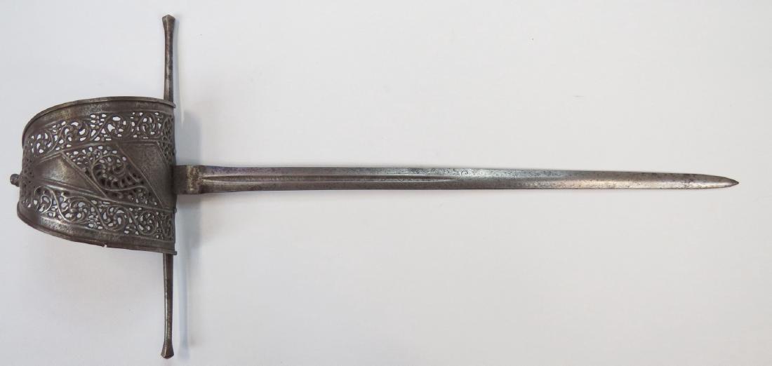 A MAIN GAUCHE DAGGER: Spanish work, the triangular steel guard finely pierced and embossed with scrolling vinework. With lightly domed pommel, broad guard with slightly expanded terminals, and copper-bound wooden grip with