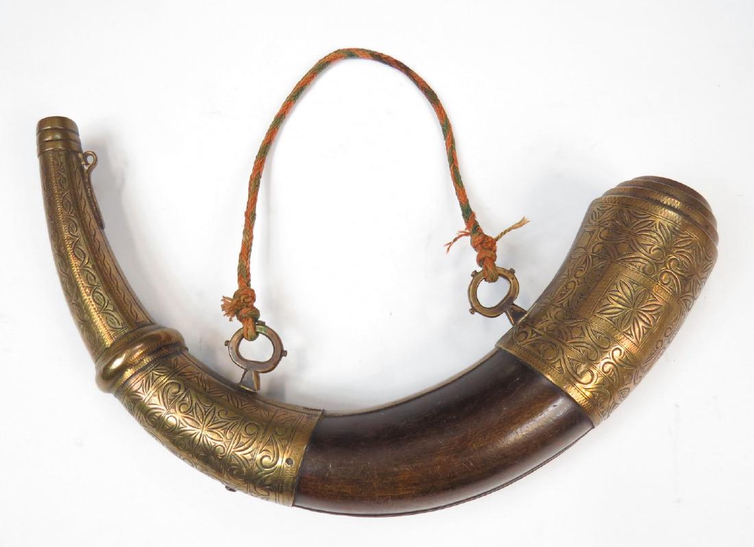 A MOROCCAN POWDERHORN: A superior example with finely-engraved brass mounts and polished horn body. 19th century. Retains its woven cord. Overall length 37 cm. Condition I