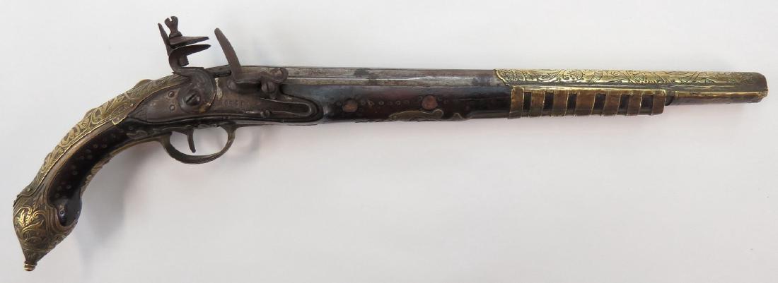 AN OTTOMAN KUBUR PISTOL: The hardwood stock mounted in well-engraved brass with conical pommel. The flint mechanism marked ROSSI, the octagonal barrel turning round toward the muzzle. First half of the 19th century. Worn. Ove