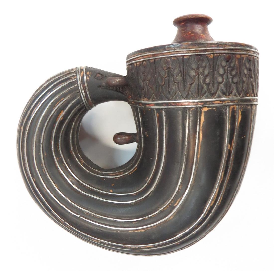 AN INDIAN BARUTDAN POWDERHORN: A fine Mughal example, the wooden body superbly carved in precise fluted panels terminating in acanthus borders and black lacquered overall with silver borders, the terminal carved as a monsterâ€��