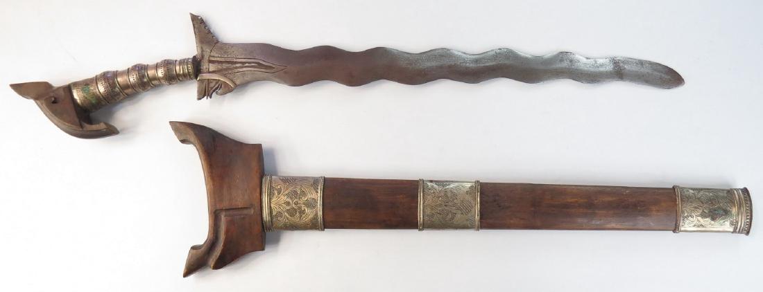 A MORO DATUS SWORD KRIS: Likely Maguindanao work, the elaborately-worked junggayan hilt typically carried by a datu or noble, with carved hardwood kakatua-form pommel and silver mounts with bands of okir engraving and profili