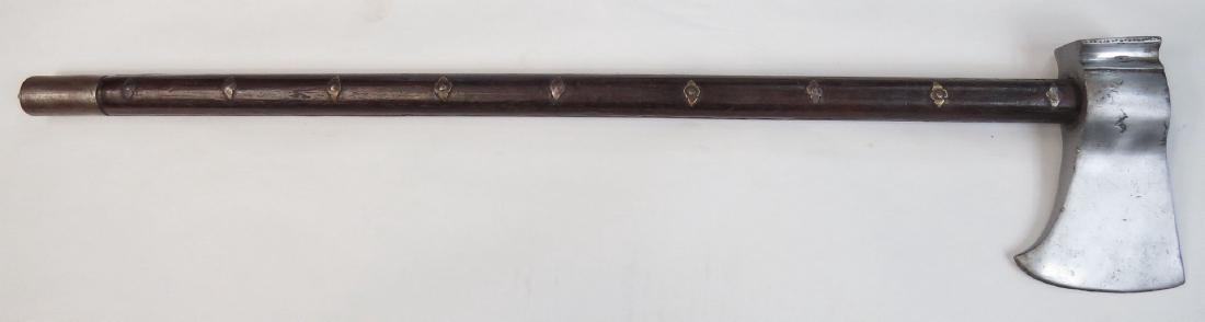 A MUGHAL TABARZIN BATTLEAXE: A horsemanâ€™s weapon, the heavy head of characteristic form with rectangular peen and slightly bearded bit. The polished hardwood grip with profiled rivets and steel finial. 17th- 18th century. 