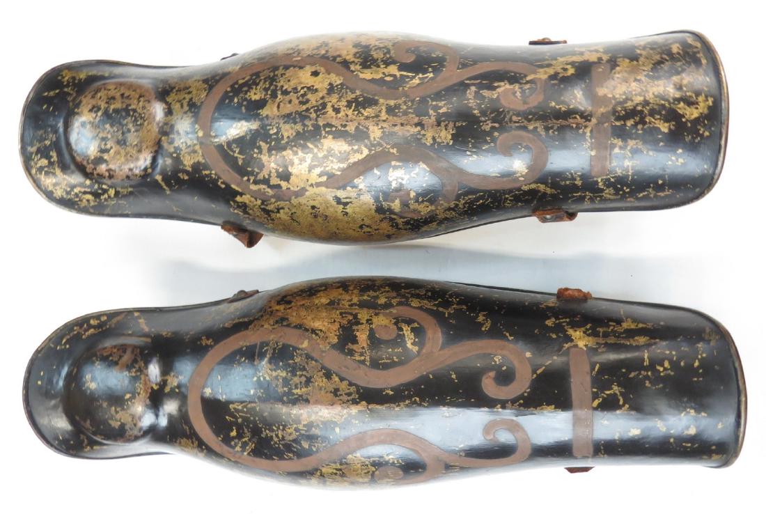 A PAIR OF VICTORIAN-ERA ARMOR GREAVES: A pair of Classical Era hoplitesâ€™ periknimides, each finely raised from a single plate of bronze, with rolled borders and original painted gilt on black decorations. Retaining original flexibil