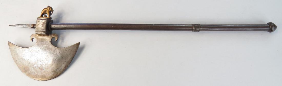 AN INDIAN BATTLEAXE: Of steel, with broad crescent head and spike finial with brass elephant peen. A dagger contained in the steel haft. 20th century. Overall length 52 cm. Condition II