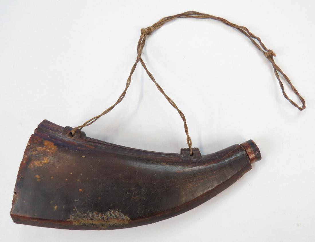 A SOUTHEAST ASIAN PRIMING FLASK: Of pressed cow horn with integral lugs, the cap with attached powder measure. 19th century. Worn. Overall length 22.9cm. Condition III