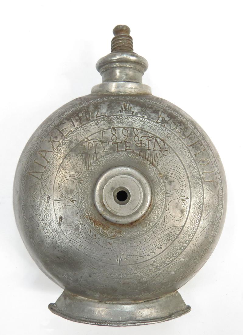 A GREEK POWDER FLASK: Dating to the Greek War of 1897-98. Of pewter, with milled borders and flanged foot, the threaded cap intact. Inscribed in Greek on the obverse, DIAHEIROS GEORGIOU 1898 ORISTEFILI, and on the reverse,