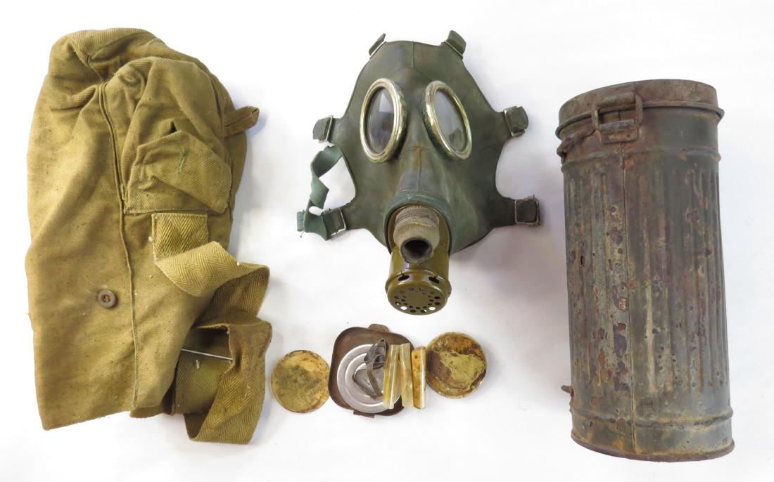 A SOVIET GASMASK: Rubber, metal and plastic, retaining some replacement part. In its steel cannister with canvas cover intact. Mid 20th century or later. As found. Canister length 26cm. Condition V