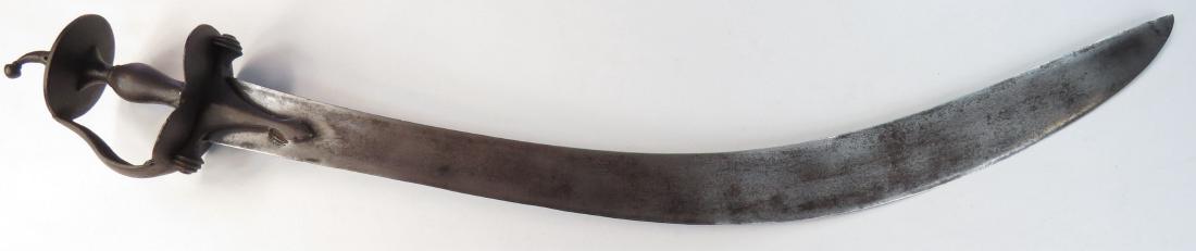 AN INDIAN EXECUTIONER’S TEGHA SWORD: Of characteristic form, with robust Indian baskethilt, the exceptionally broad blade T-backed and heavily curved. Early 18th century. Minor crack to tip. Overall length 87.4 cm. Condition IV