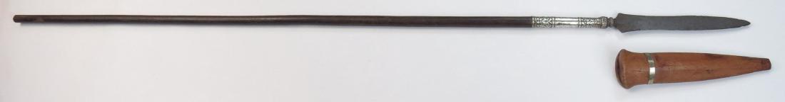 A JAVANESE SPEAR: The handwrought, pattern-welded damascus steel head of characteristic form with flared and pierced lower terminals and moldings to base. Retained to the polished hardwood haft with a long, finely embo