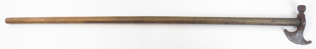 A HUNGARIAN FOKOS AXE: An older example, the massive steel head with hammer peen, struck with marks. On its characteristically long hardwood haft with brass nailhead decoration. 19th century. Well worn. Overall length 86cm.