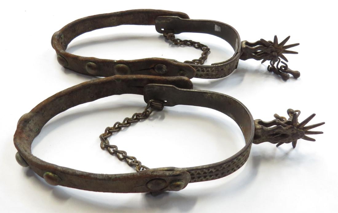 A PAIR OF WESTERN SPURS: Elaborately modelled, retaining rowels, jingles, leathers and buttons. Early 20th c. Well worn, heel band with period riveted repair. Appear to be Buermann Eldorado, unmarked. Overall length 25cm. Con