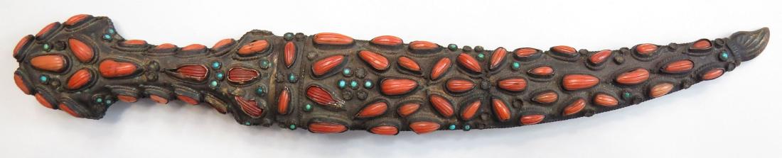 AN OTTOMAN COURT DAGGER: hilt and scabbard set with reeded corals and tiny turquoises overall, the reverse with engraved floral motifs. The blade lightly-curved and double edged, inlaid at the forte on either side. Latter 19t