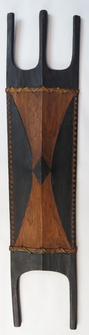 A PHILIPPINES SHIELD: Kalinga People, carved a single section of hardwood in characteristic form, with carved geometrical carved borders and central motif heightened with pigment, and rattan bindings intact; the reverse wi