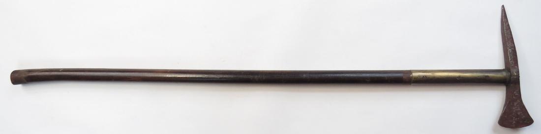 A HUNGARIAN FOKOS AXE: The steel head with backspike. On its long hardwood haft with brass locket. 20th century. Head corroded. Overall length 75.5cm. Condition III