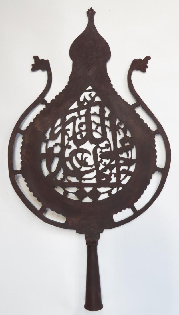 A RARE PERSIAN ALIM BATTLE STANDARD: Of finely wrought steel with russet finish, the rim with dragon head terminals, the body pierced with ALLAH! MUHAMMAD! ALI! amongst vinework and terminating in the Hand of ‘Ali. With expanded, rimme