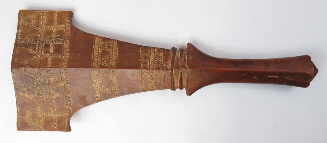 A RARE SAMOAN EARED CLUB: Of characteristic form, carved of dense reddish hardwood, intricately incised with geometrical designs filled with lime. Late 19th century. Worn, lower flanges chipped. Overall length 56.5cm. Conditio