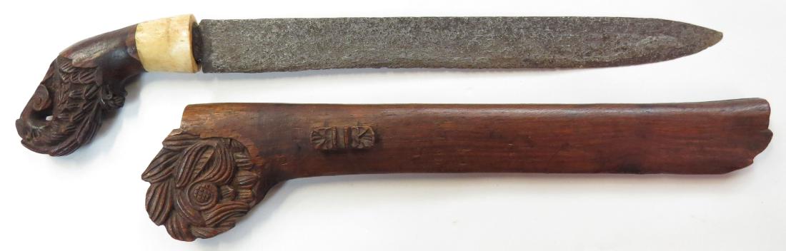 AN INDONESIAN BADEK DAGGER: A large example, mounted in well-carved wood with bone ferrule, with handforged pattern-welded blade. 19th century. Worn. Overall length 44.2cm. Light wear. Condition II
