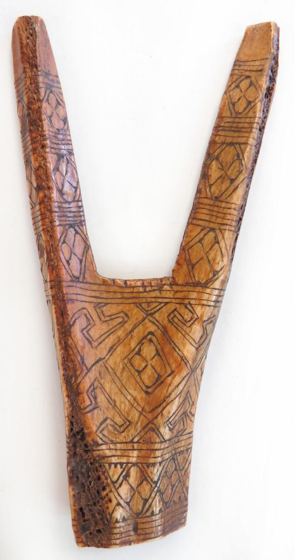 A TIMORESE SLINGSHOT: Carved of a section of antler with incised geometrical motifs overall.20th century. Worn. Overall length 16cm. Condition III