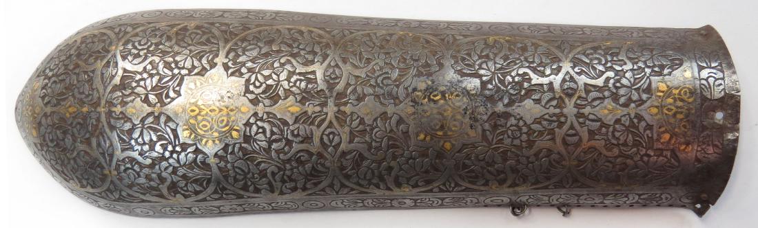 A PERSIAN BAZUBAND ARMGUARD ARMOR: Early Qajar Dynasty, raised from a single plate and finely chiseled overall in flowering vinework with gold embellishments. Early 19th century. Overall length 30.2cm. Condition II