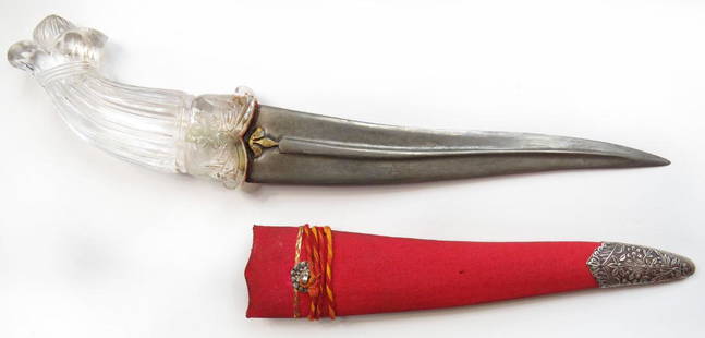 AN INDIAN KHANJAR DAGGER: The rock-crystal grip with pommel carved as a lotus, with floral motifs at the base. The curved, double-edged blade with pronounced central rib forged of wootz damascus steel and terminating in an arm