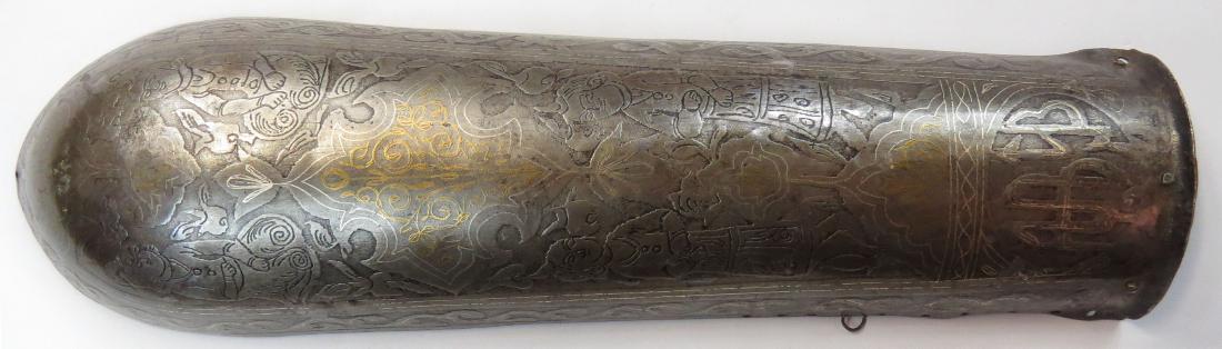 A PERSIAN BAZUBAND ARMOR ARMGUARD: Qajar Dynasty, raised from a single plate and deeply etched overall, with gold and silver inlay. Mid-19th century. Worn overall. Overall length 31.6cm. Condition III