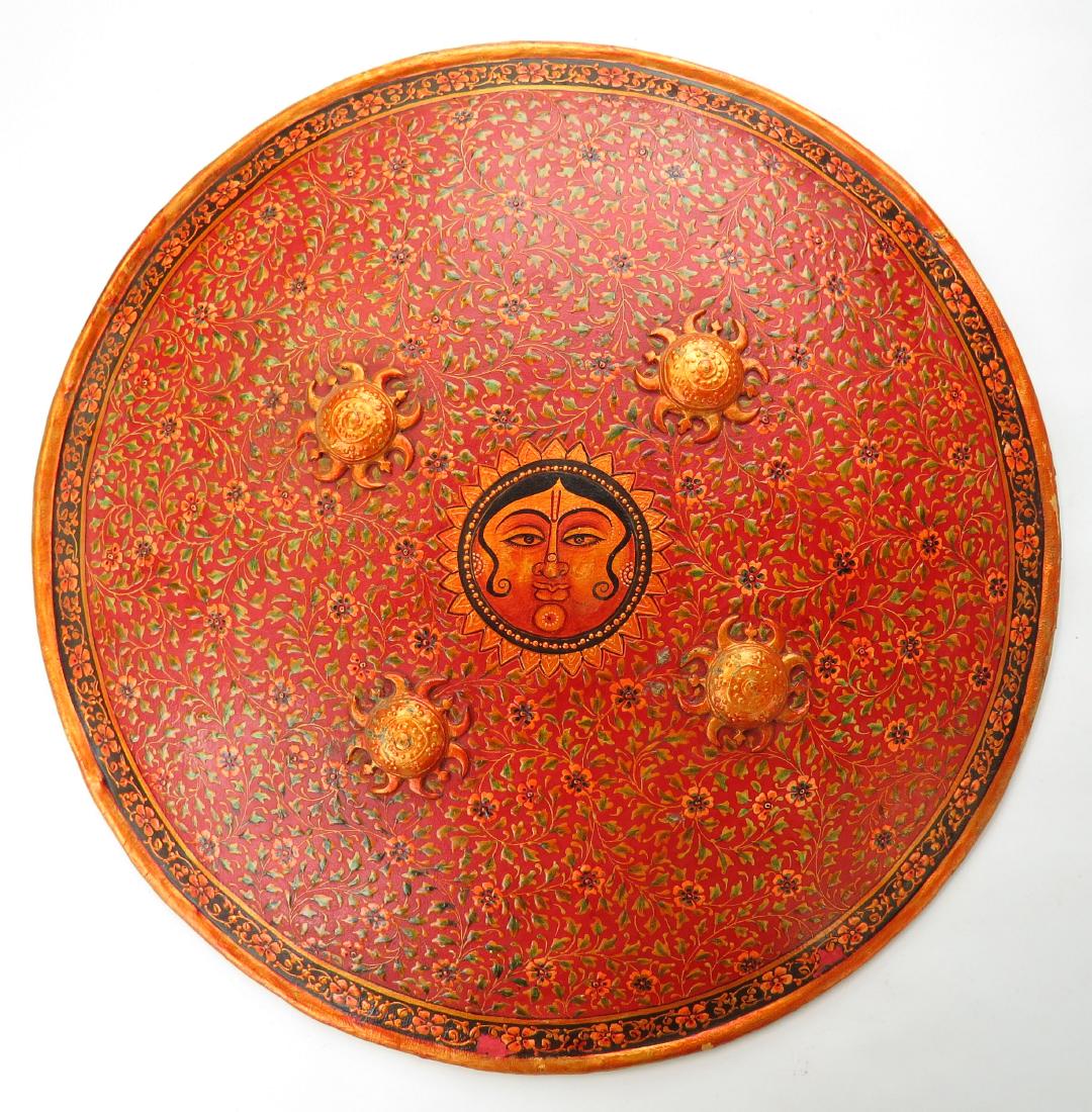 AN INDIAN DHAL SHIELD: Superbly hand-painted metal covered entirely in flowering vinework with Surya, the Sun God, depicted at the center. 20th century. Light wear. Diameter 44.6cm. Condition III