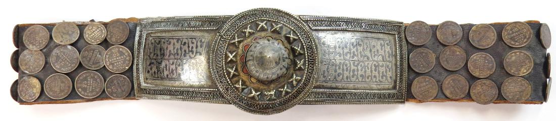 A ZAPOROZHIAN COSSACK HETMANS BELT: Mounted entirely in silver, the large buckle made in two sections of chiseled, engraved and nielloed silver with beaded borders, the broad leather belt set with numerous dated 19th century Imperial Ru