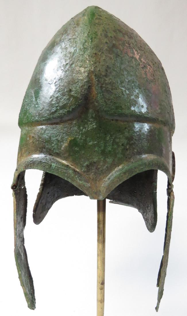 A GREEK BRONZE CHALCIDIAN HELMET: Of hammered bronze, a type evolved from the Corinthian helmet. The Chalcidian form first appears in art on an early fifth century b.c.e. amphora believed to have been painted at Chalcis, Euboea; this 