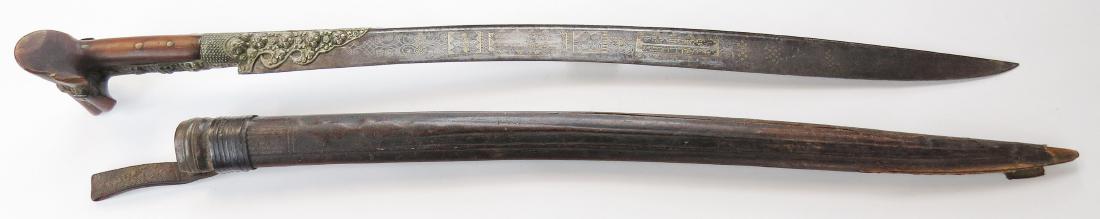 AN OTTOMAN YATAGHAN SWORD: With large, horn ears in the Balkan style, mounted in embossed and engraved silver. The well-wrought, fullered blade elaborately inlaid with Ottoman poetry and Gordian knot motifs in gold and silver,