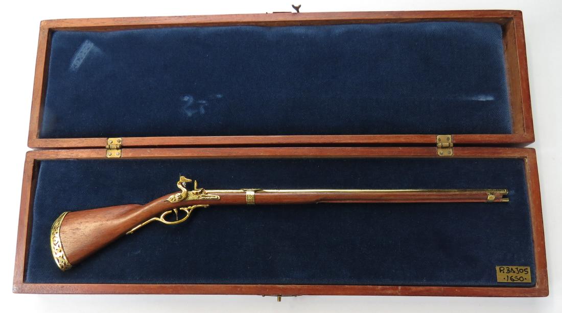 MINIATURE DUTCH SNAPHAUNCE MUSKET BY EDUARDO RUIZ: A miniature Dutch snaphaunce musket made entirely by hand, the stock carved of hardwood with snaphaunce, mounts, mechanism, barrel and triggerguard all superbly detailed in metal. In its fitted handma