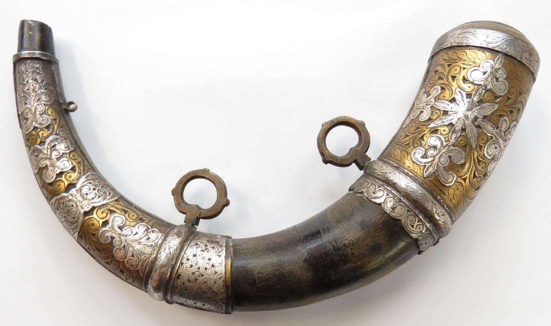 A MOROCCAN POWDERHORN: A superior example with finely-engraved brass and silver mounts and horn body. 19th century. Wear to mounts. Overall length 32.5cm. Condition II