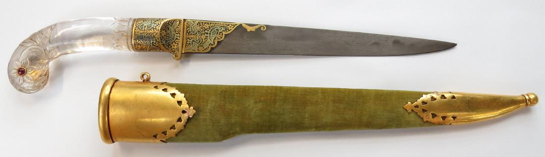 A FINE ROCK CRYSTAL-HILTED INDIAN DAGGER: Mughal work, the grip carved of a single section of rock crystal, with characteristic rolled grip and flowering lotus motifs, the pommel with a ruby set in gold on either side. The bolsters and forte