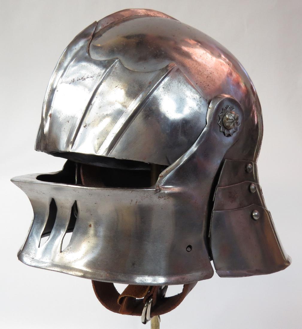 A REPLICA SALLET HELMET: Handwrought of steel with fluted skull and lamellar neck, the visor released by a spring catch. Fully lined, with chin strap. 20th century. Height 26.5cm. Condition III