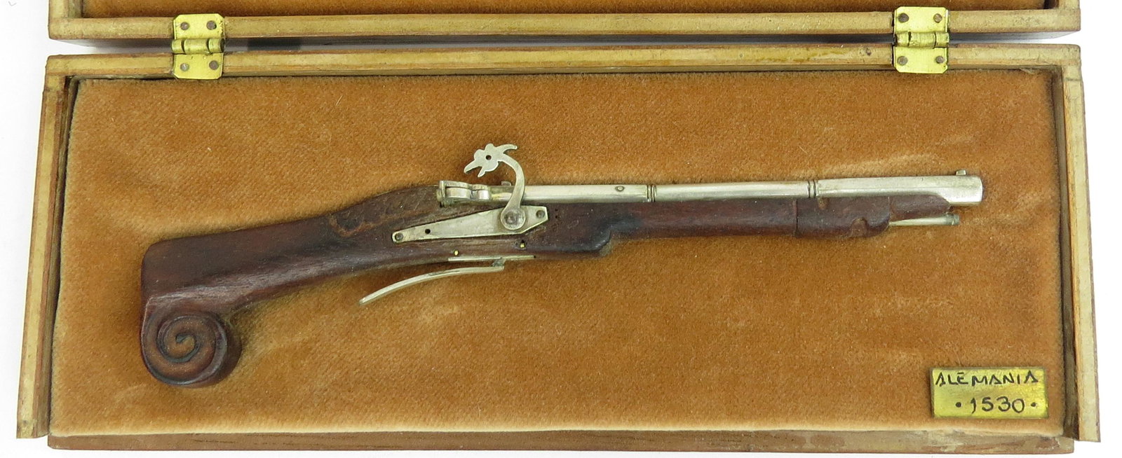 MINIATURE GERMAM MATCHLOCK CARBINE BY EDUARDO RUIZ: A miniature German carbine made entirely by hand, the stock finely carved of hardwood with matchlock mechanism, barrel, triggerguard and lock all well-detailed in metal. In its fitted handmade hardwoo