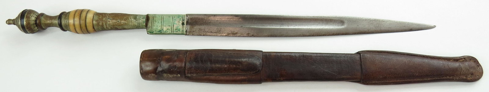 A SOUTH AMERICAN DAGGER: With turned bone grip and lengthy ferrule, single-edged blade with central fuller. In its leather sheath. Late 19th century. Well worn. Overall length 34cm. Condition III