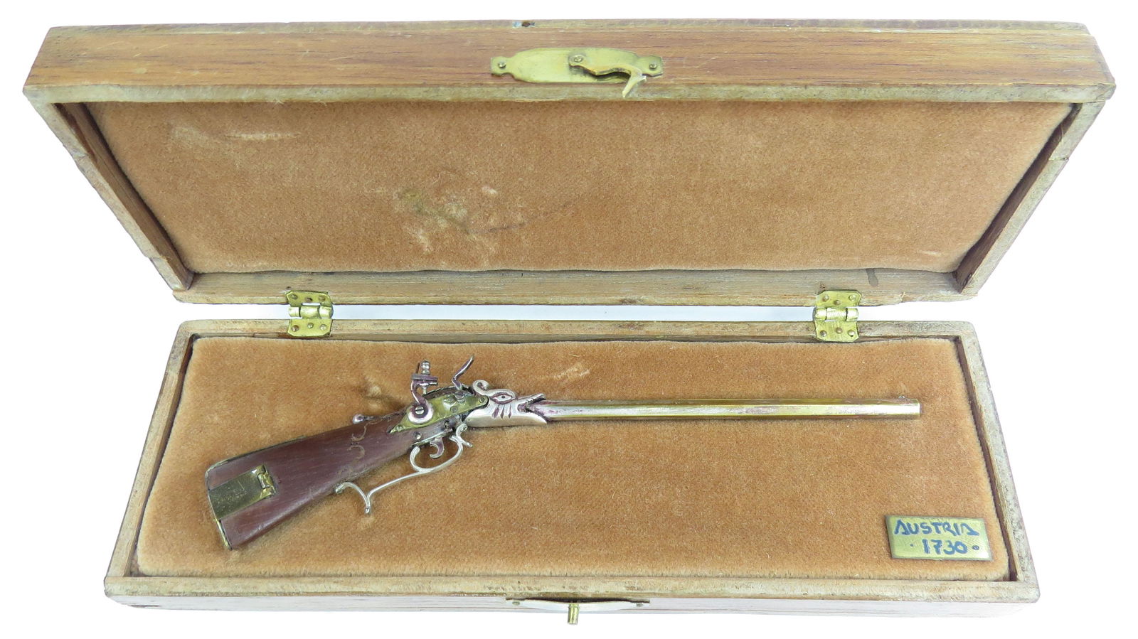 A FINE MINIATURE AUSTRIAN CARBINE BY EDUARDO RUIZ: A miniature flintlock carbine made entirely by hand, the stock carved of hardwood with percussion mechanism, barrel, triggerguard and appliques all superbly detailed in metal. In its fitted handmade h