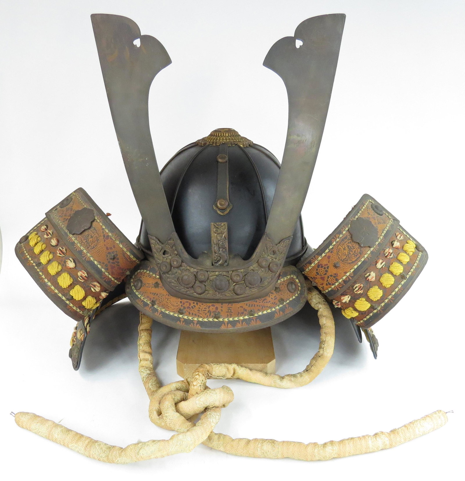 A JAPANESE KABUTO HELMET: Meiji era, the steel bowl lacquered black with elaborate applied brass decoration, brass antler maedate intact, the steel shikoro with large, rectangular fukurin. Retains its liner and binding cord. L