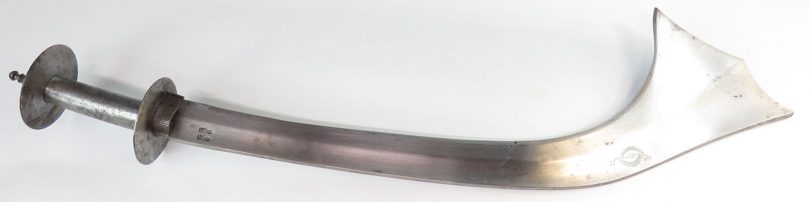 A NEPALESE KORA SWORD: A rare example, with broad blade in the traditional elephant-ear form, with raised central ridge and scrolled tip chiseled with a sun. Hilt of steel with disk guards and segmented, domed pommel. Latte