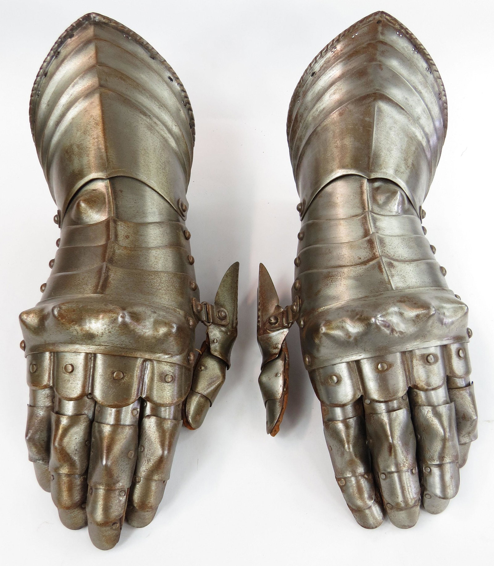 A PAIR OF VICTORIAN-ERA ARMOR GAUNTLETS: Finely handwrought, the pointed cuffs fluted, with rolled and roped borders. The lames articulated and embossed at the knuckles, fingers intact. First quarter of the 17th century. Worn. Overall length