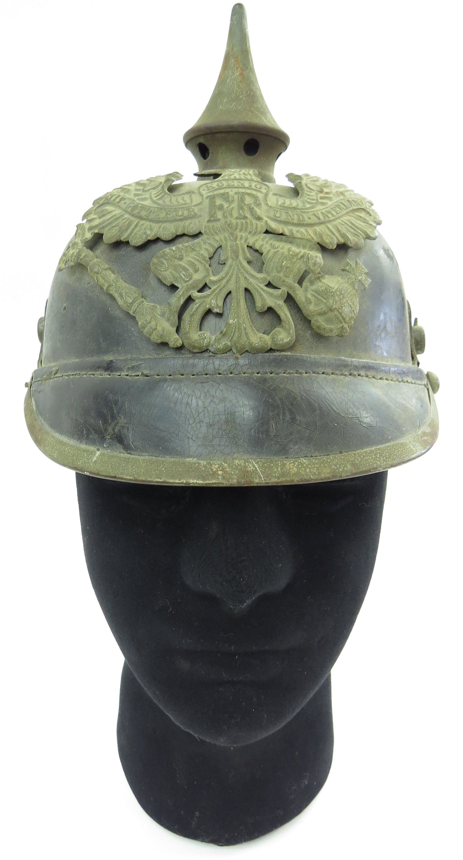 A PRUSSIAN M 1915 PICKELHAUBE HELMET: Of leather, with brass mounts including top spike and eagle plate with motto and FR monogram. Beginning half of the 20 th century. Well worn, chinstrap lacking. Overall height 24cm. Condition III