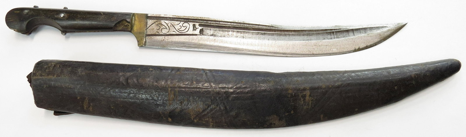 AN OTTOMAN SURMENE DAGGER: A large example, the characteristic eared horn grip with deep fingerstall and lightly-recurved, finely fullered blade struck with a maker’s mark reading ALI. In its tooled leather-covered wooden sca